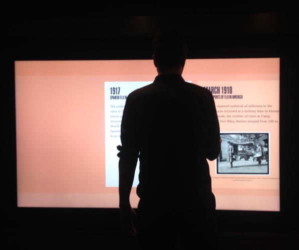 a person's silhouette against a large touch screen